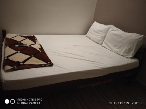 a unmade bed with white sheets and a brown at Sai Baba Service Apartments in Chennai