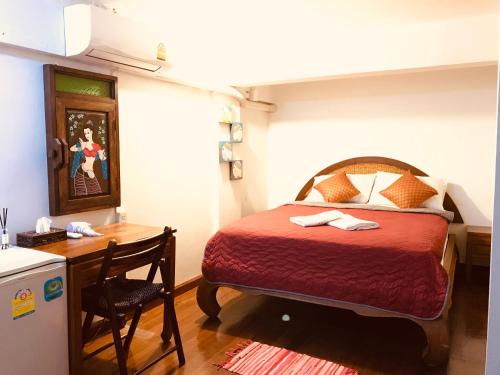 1 dormitorio con cama, escritorio y mesa en Bee Friend Hostel, en Chiang Mai
