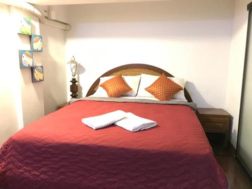a bedroom with a red bed with two towels on it at Bee Friend Hostel in Chiang Mai