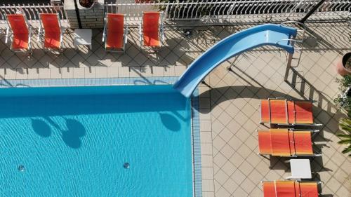 an overhead view of a swimming pool with chairs and a water slide at Hotel Cosmos in Rimini