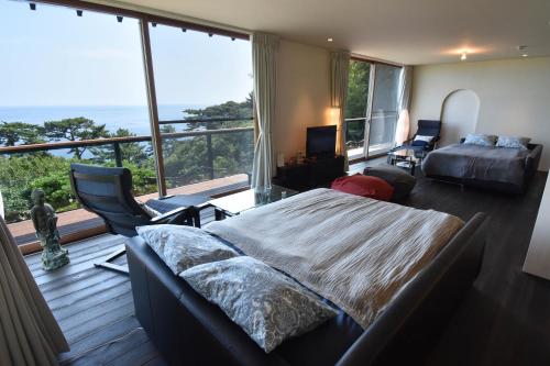une chambre avec un lit et une grande fenêtre dans l'établissement 伊豆稲取テラス-寛道-, à Shimoda