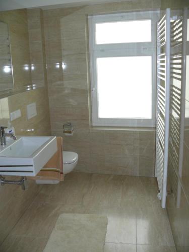 a bathroom with a sink and a toilet and a window at Ferienwohnung Speyer in Speyer