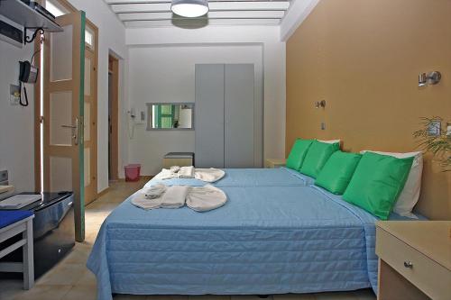 a bedroom with a blue bed with green pillows at Xenones Lindos in Líndos