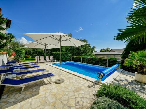 a pool with chairs and an umbrella and a slide at Apartment Lucija by Interhome in Matulji