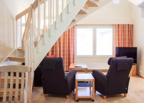 a living room with two chairs and a staircase at Spa Hotel Rauhalahti in Kuopio