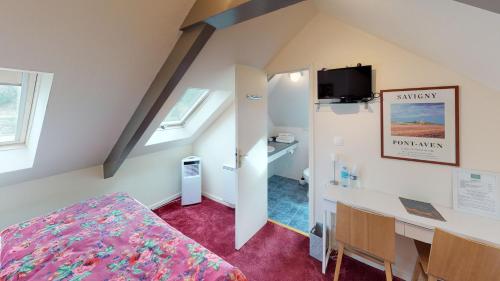ein Schlafzimmer mit einem Bett und einem Schreibtisch in einem Zimmer in der Unterkunft Hotel de charme Les Mimosas in Pont-Aven