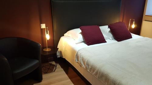 a hotel room with a bed and a chair at Le Beaugency in Beaugency