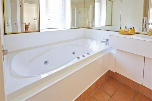 a white bathroom with a tub and a sink at Pioneer Waterfront Apartments in Paihia