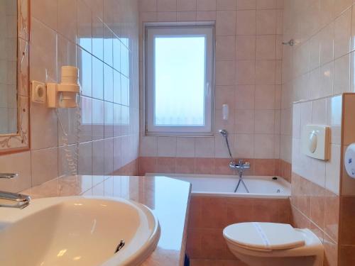 a bathroom with a tub and a toilet and a sink at SANTE Hévíz in Hévíz