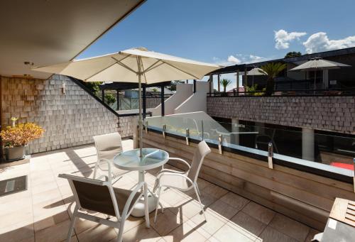 a patio with a table and chairs and an umbrella at Pioneer Waterfront Apartments in Paihia