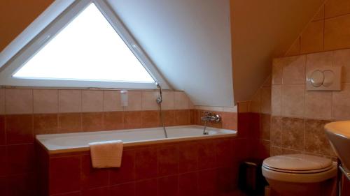 a bathroom with a bath tub and a window at SANTE Hévíz in Hévíz