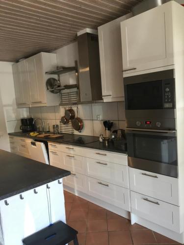 uma cozinha com armários brancos e um balcão preto em skummeslöv B & B em Laholm