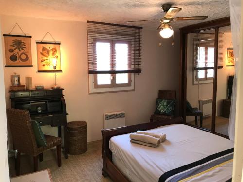 a bedroom with a bed and a desk and windows at Mas du tilleul in Callian