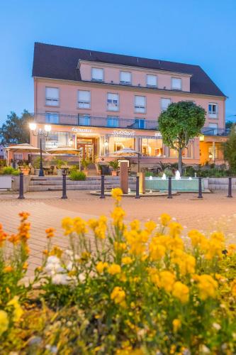 a pink building with yellow flowers in front of it at Hôtel Restaurant Le Bristol in Niederbronn-les-Bains