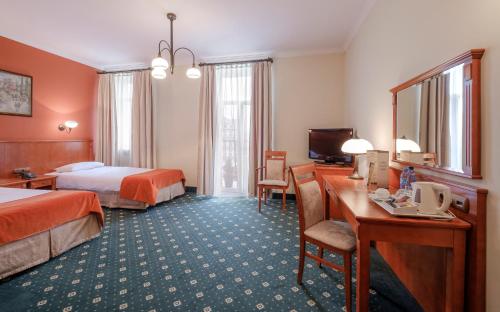 a hotel room with two beds and a desk at Hotel Hetman in Warsaw