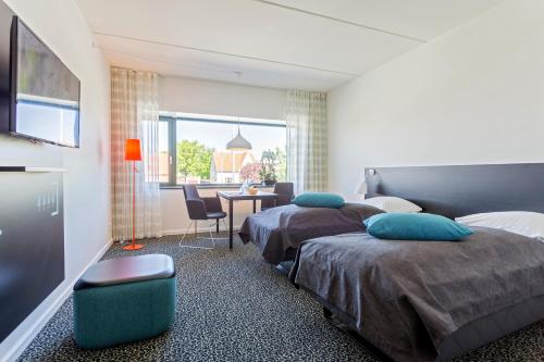 a hotel room with two beds and a desk and a table at Glostrup Park Hotel in Glostrup