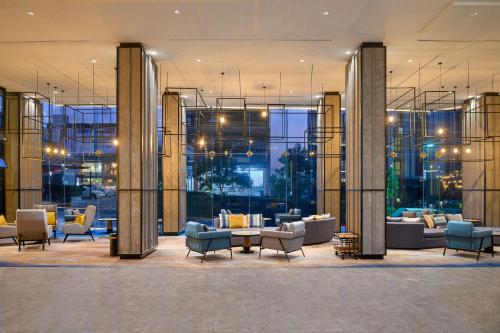 a lobby with couches and chairs in a building at Holiday Inn & Suites Siracha Laemchabang by IHG in Si Racha