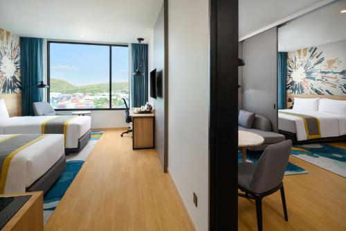 a hotel room with two beds and a desk and a table at Holiday Inn & Suites Siracha Laemchabang by IHG in Si Racha