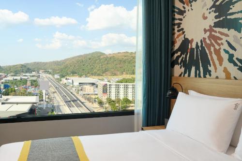 a bedroom with a bed and a large window at Holiday Inn & Suites Siracha Laemchabang by IHG in Si Racha