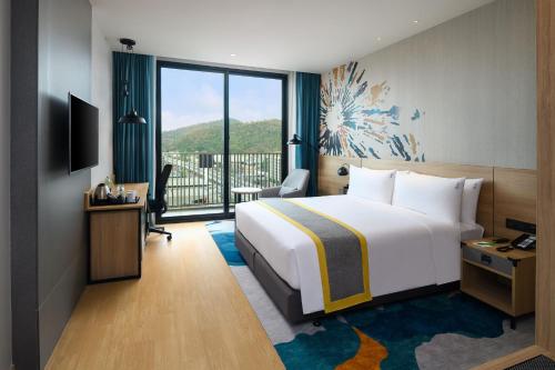 a hotel room with a bed and a large window at Holiday Inn & Suites Siracha Laemchabang by IHG in Si Racha