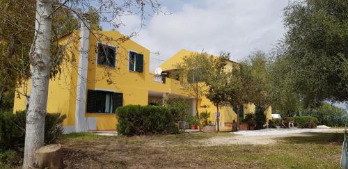 a yellow house with trees in front of it at Le Caracol - Appartamenti immersi nel verde della campagna e a 1 chilometro da Orosei in Orosei