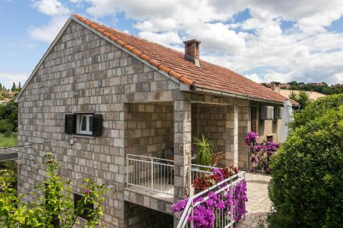 een bakstenen huis met een balkon en paarse bloemen bij Apartments Maria in Koločep