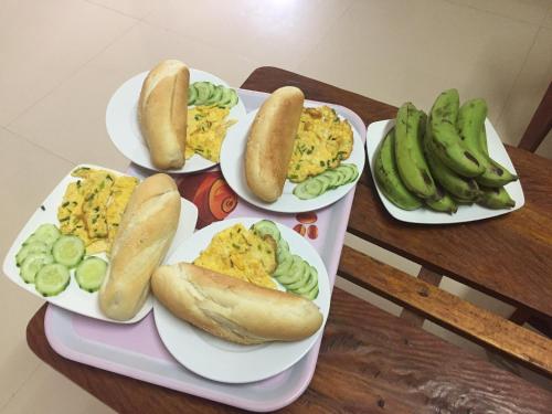 Ein Tisch mit vier Tellern Essen, darunter Hotdogs und Bananen. in der Unterkunft Applebee's Homestay in Phong Nha