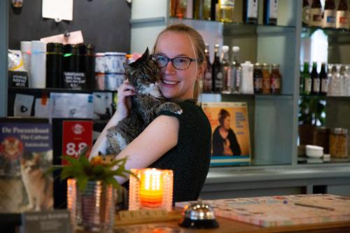 a woman standing behind a counter holding a cat at Hotel La Bohème in Amsterdam