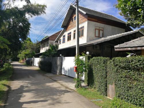a white house with a fence next to a street at Ping Pool Villa 2 in Mae Rim