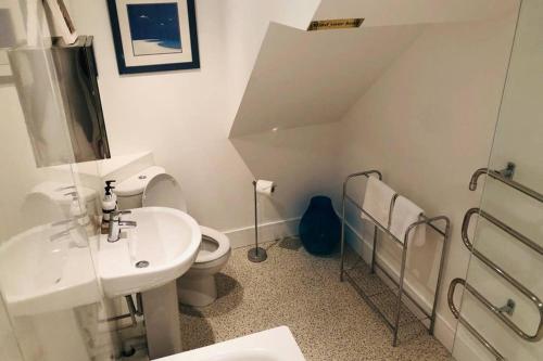 a white bathroom with a sink and a toilet at Bay House Lobber Port Isaac Apartment with Sea Views in Port Isaac