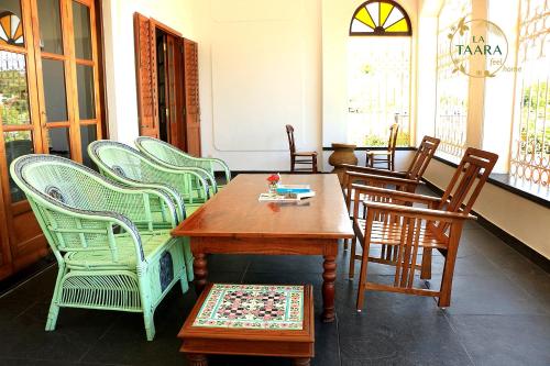 a dining room with chairs and a wooden table and a table and chairs at La Taara - Feel Home in Auroville