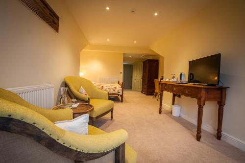 a living room with chairs and a television and a desk at Dene House Farm in Longframlington