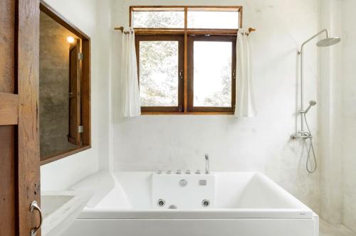 a white bathroom with a tub and a window at Ping Pool Villa 2 in Mae Rim
