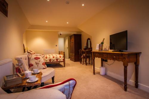uma sala de estar com um sofá e uma mesa com uma televisão em Dene House Farm em Longframlington