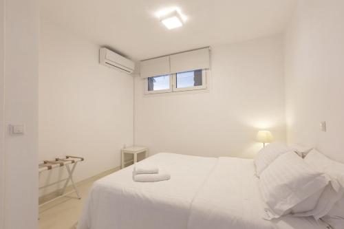 a white bedroom with a white bed and a window at Apartment with a sea view and swimming pool, in the area of Koundouros in Koundouros