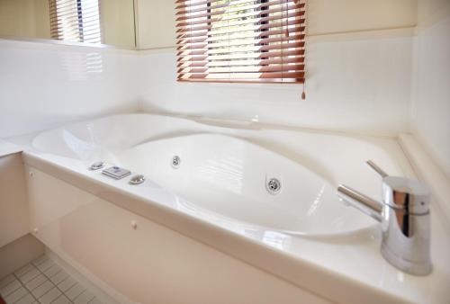 a white bath tub in a bathroom with a window at Pioneer Waterfront Apartments in Paihia