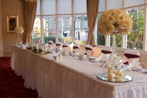 Una larga mesa blanca con una flor. en Victoria Hotel, en Kirkcaldy