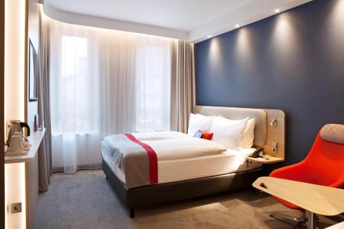 a hotel room with a bed and a red chair at Holiday Inn Express - Mülheim - Ruhr by IHG in Mülheim an der Ruhr