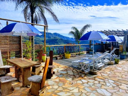 eine Terrasse mit Tischen, Stühlen und Sonnenschirmen in der Unterkunft Pousada Ecologica Vale das Cores in Lavras Novas