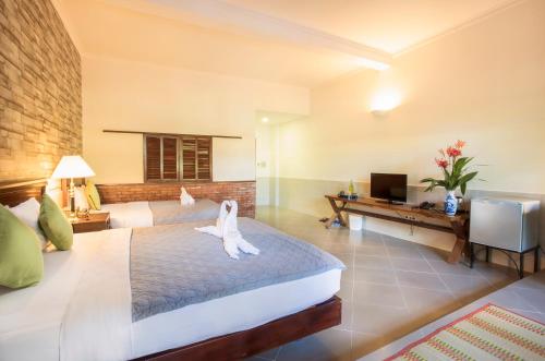 a bedroom with a bed and a desk and a television at Cat Tien Jungle Lodge in Cat Tien