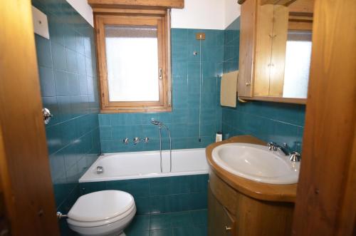y baño con aseo, bañera y lavamanos. en Punta Nera: appartamento con giardino e WIFI en Zuel