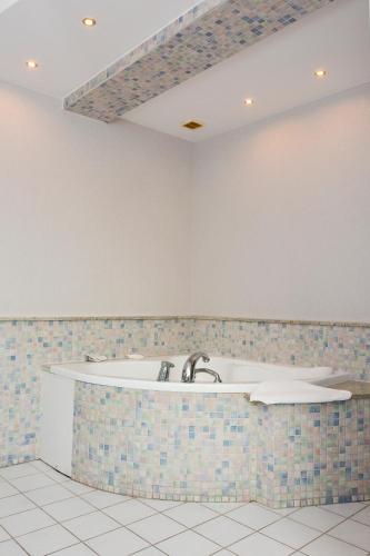 a bath tub in a room with a tile wall at Willa Bryza in Gdynia