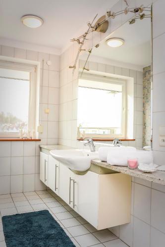 a white bathroom with two sinks and a mirror at Willa Bryza in Gdynia