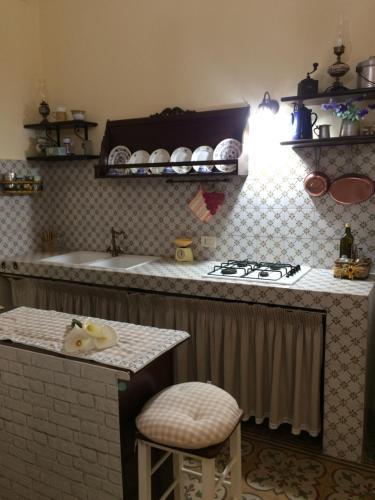 a kitchen with a stove and a sink and a stool at Villa Ylenia Marsala in Marsala