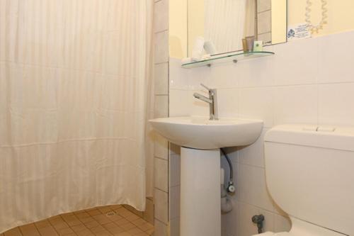 Baño blanco con lavabo y aseo en Ocean View Motel, en Perth
