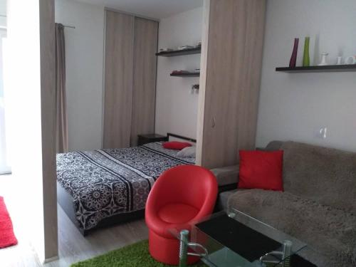 1 dormitorio con 1 cama, 1 silla roja y 1 sofá en Apartmán Mery, en Podhájska