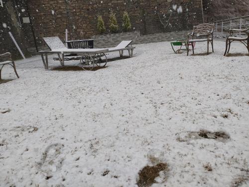 a picnic table and benches covered in snow at Kanishka Retreat Resort Chail in Chail