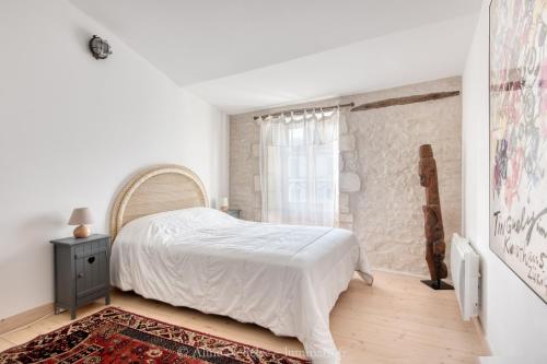 a white bedroom with a bed and a window at Maison Salicorne in La Flotte