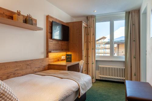 
a bedroom with a bed and a television at Hotel Jägerhof in Zermatt
