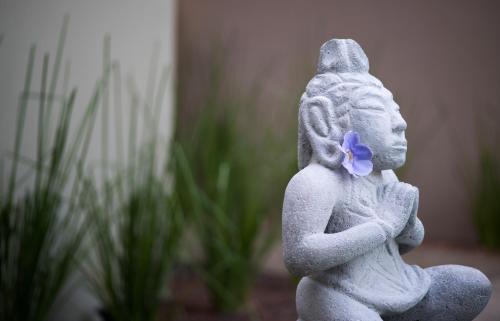 a small statue of a girl with a purple flower at Tamarindo Bay Boutique Hotel, Apartments & Suites in Tamarindo
